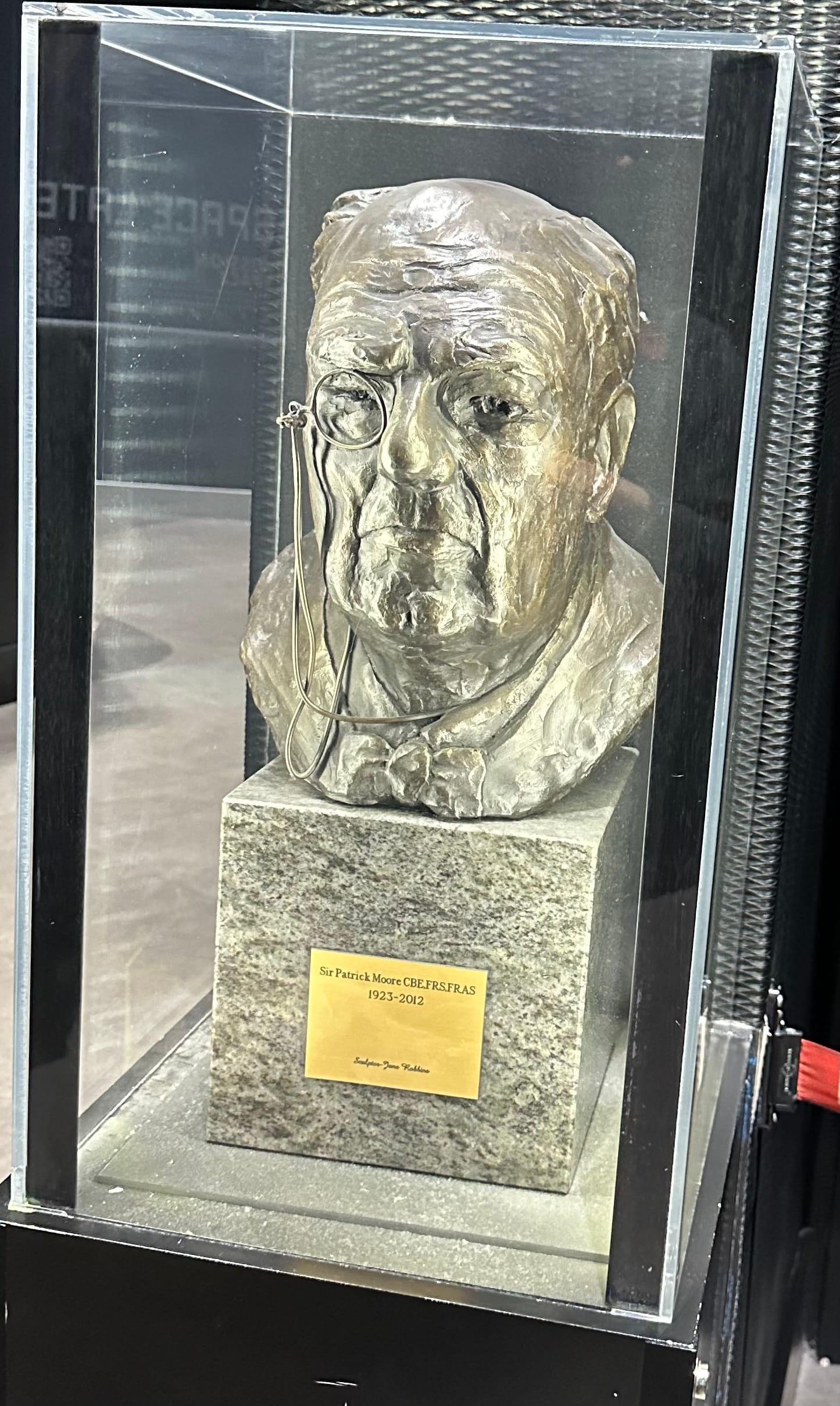 A bust of Sir Patrick Moore with a plaque that reads "Sir Patrick Moore CBE,FRS,FRAS 1923 - 2012 Sculptor Jane Robbins"