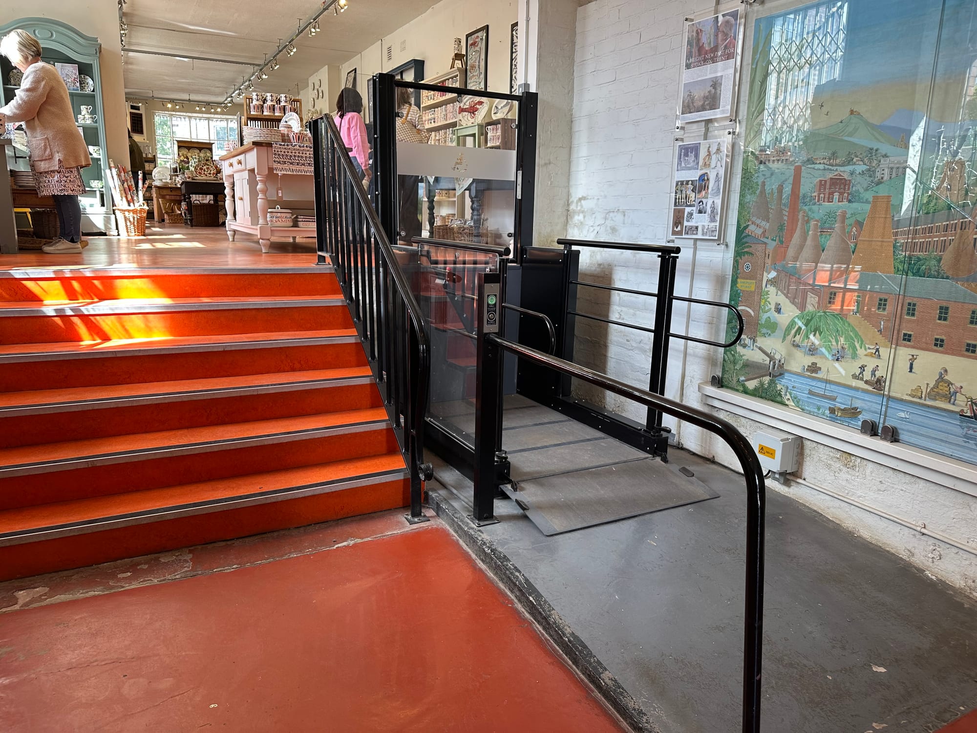 There are six red stairs heading up into the shop area. To the right of the stairs is a small lift.