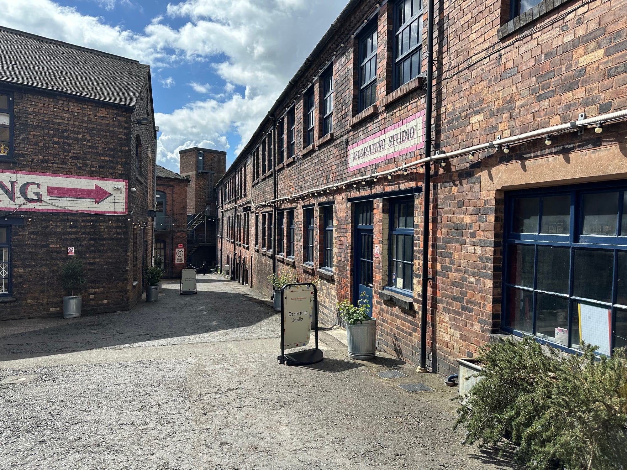 Part of the courtyard area with old buildings around it. On the right a sign painted on the wall says Decorating Studio. Another sign in front of a door on the right also say Decorating Studio