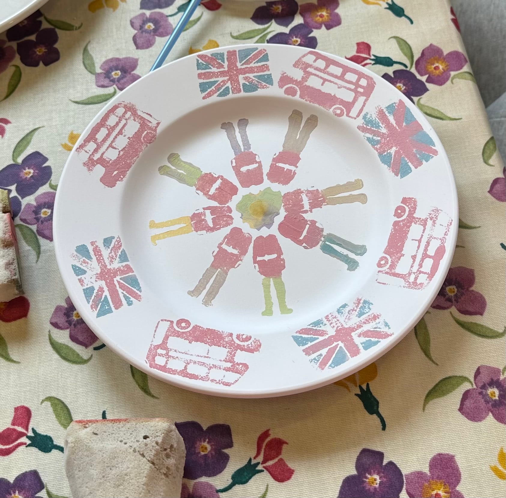 This plate has red buses and Union Jacks around the edge with guards (soldiers) in the middle