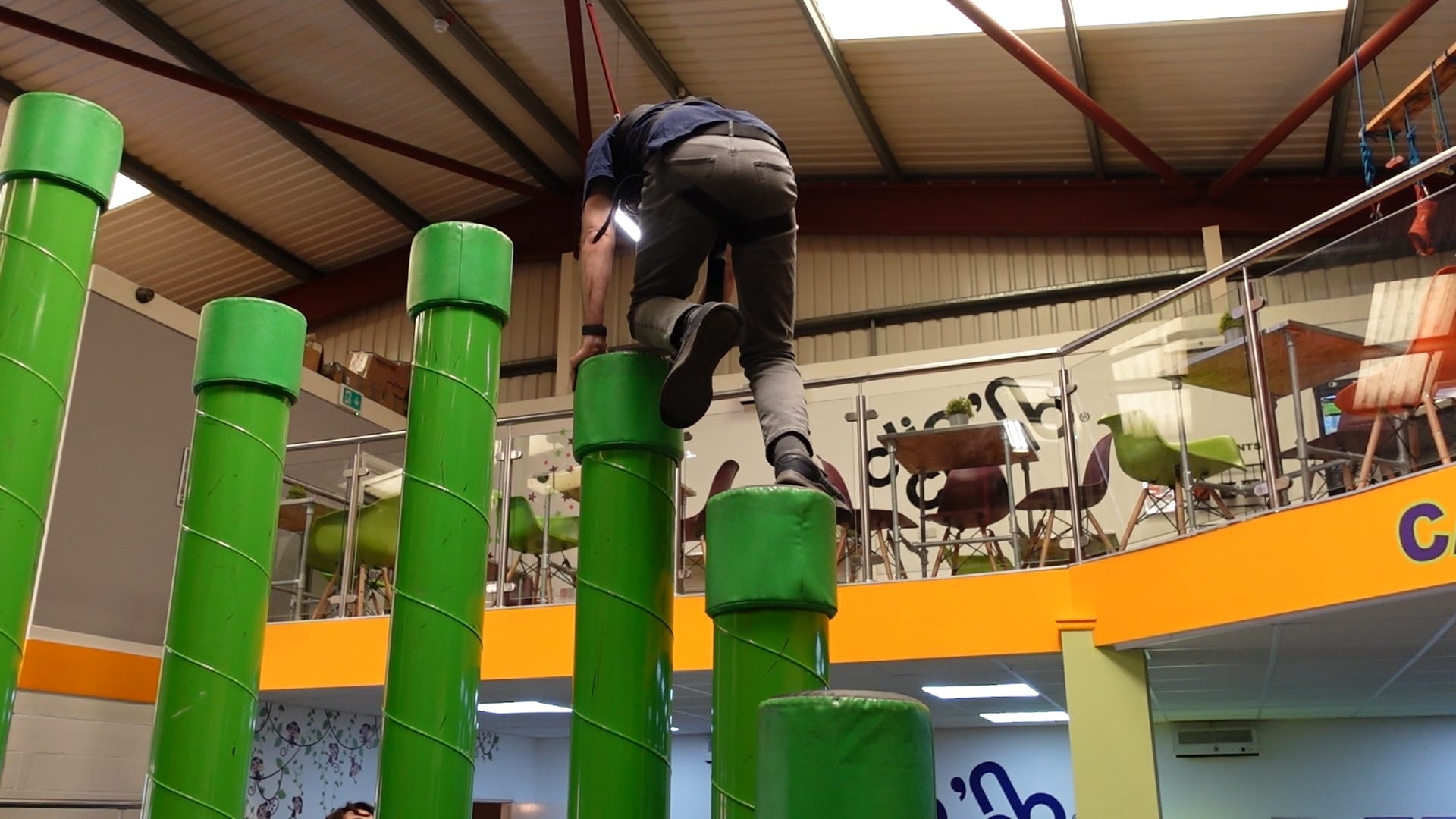 John on the green poles of "Stairway to Heaven". He has his right foot on a lower pole and his left knee and hands on the higher pole in front of him