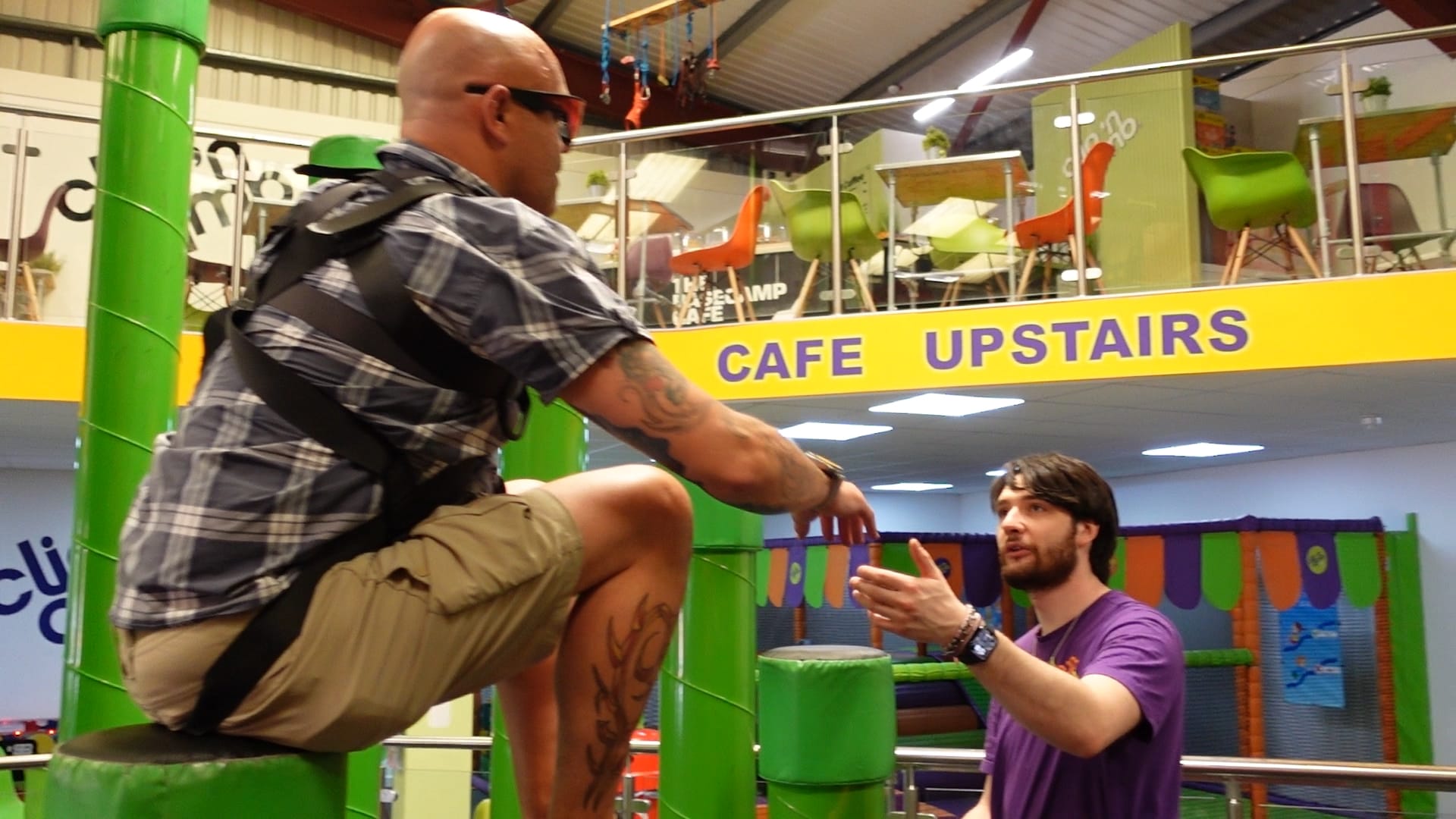 Wayne is sitting on a green pole with the instructor in front of him. The instructor is telling him where the next pole is