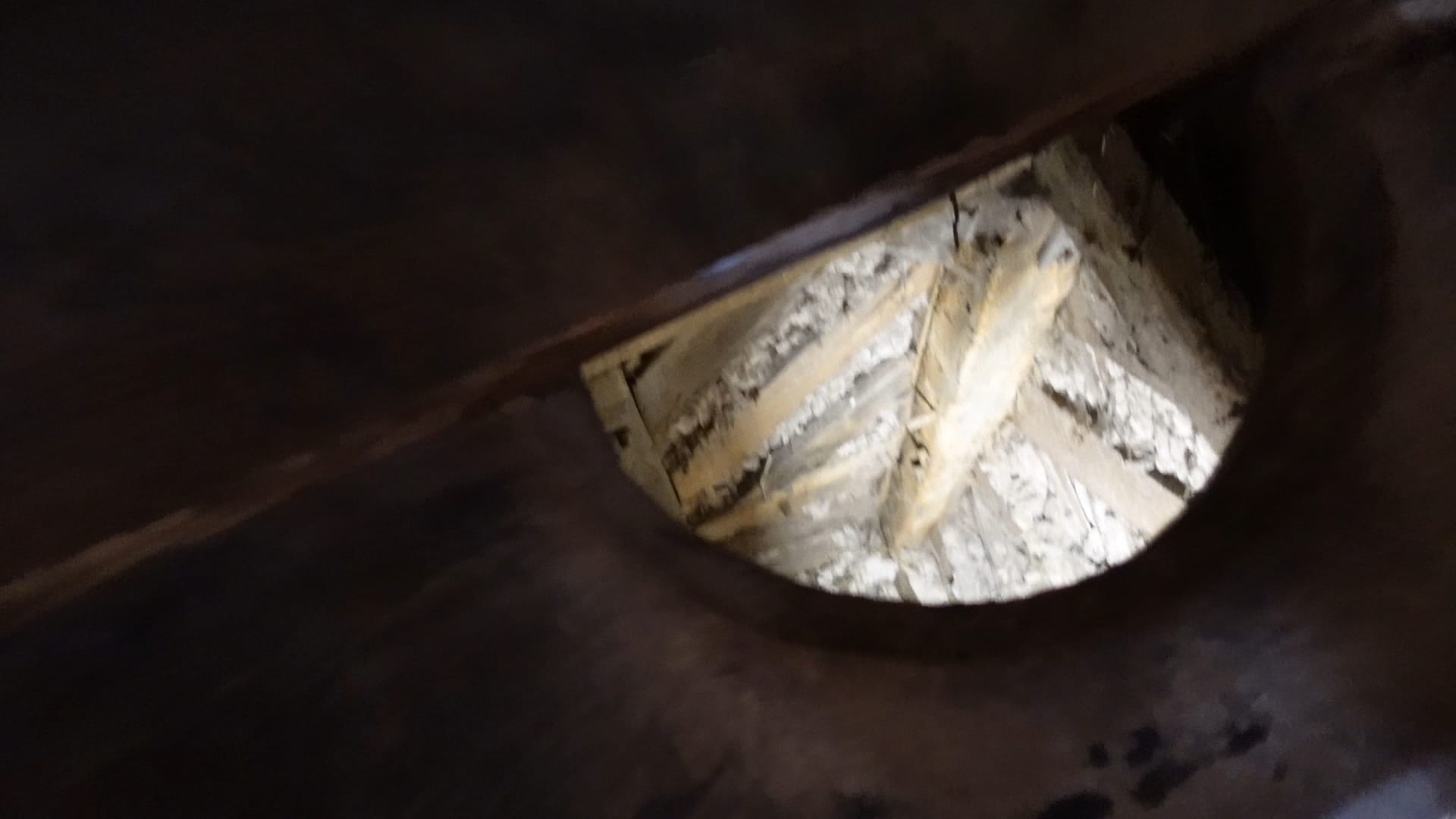 The privy looks like a bench with a hole in it. Daylight can be seen coming up through the hole, as the privy empties straight into the moat!
