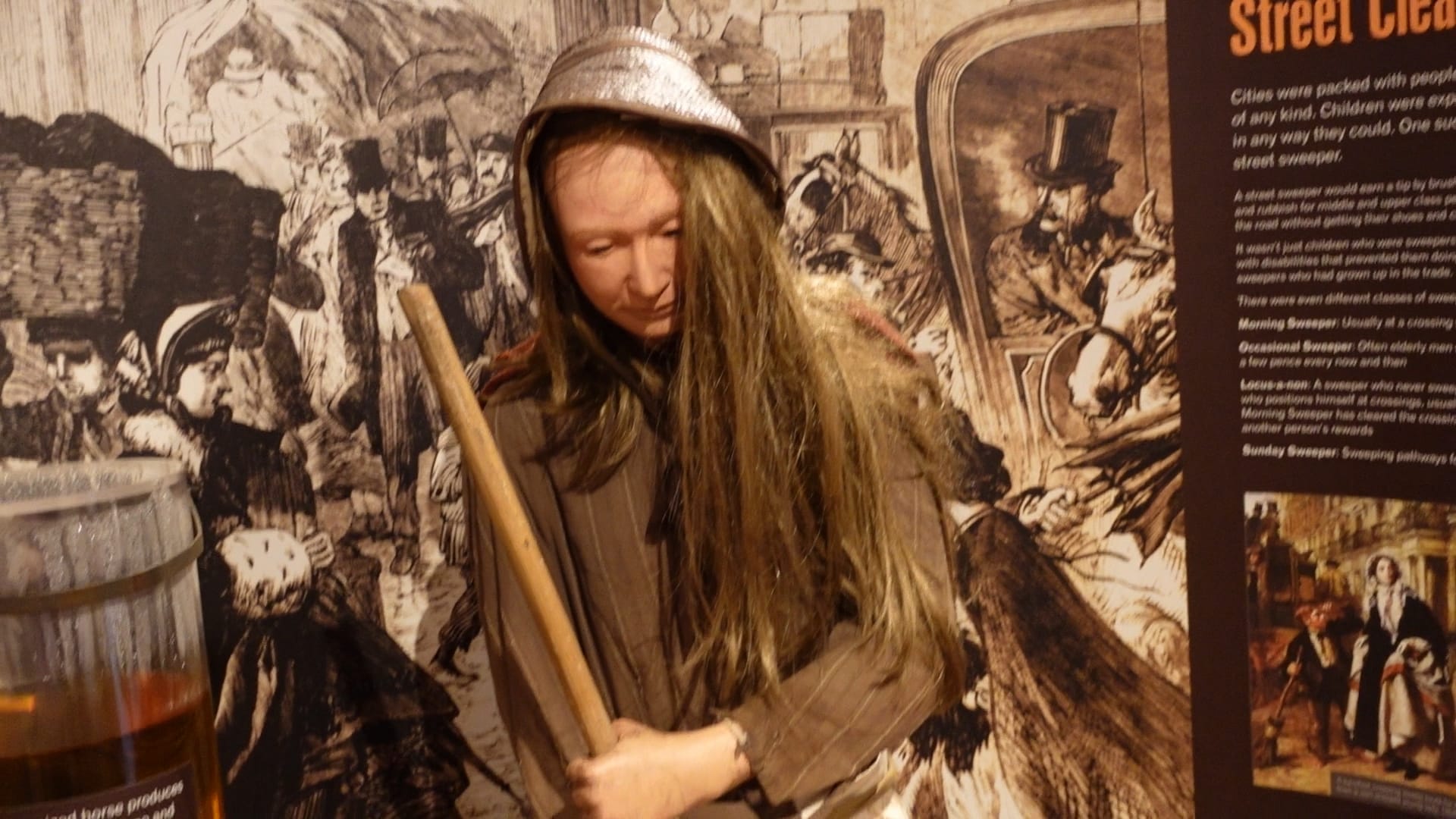 A model of a woman holding a broom, cleaning the streets in Victorian times