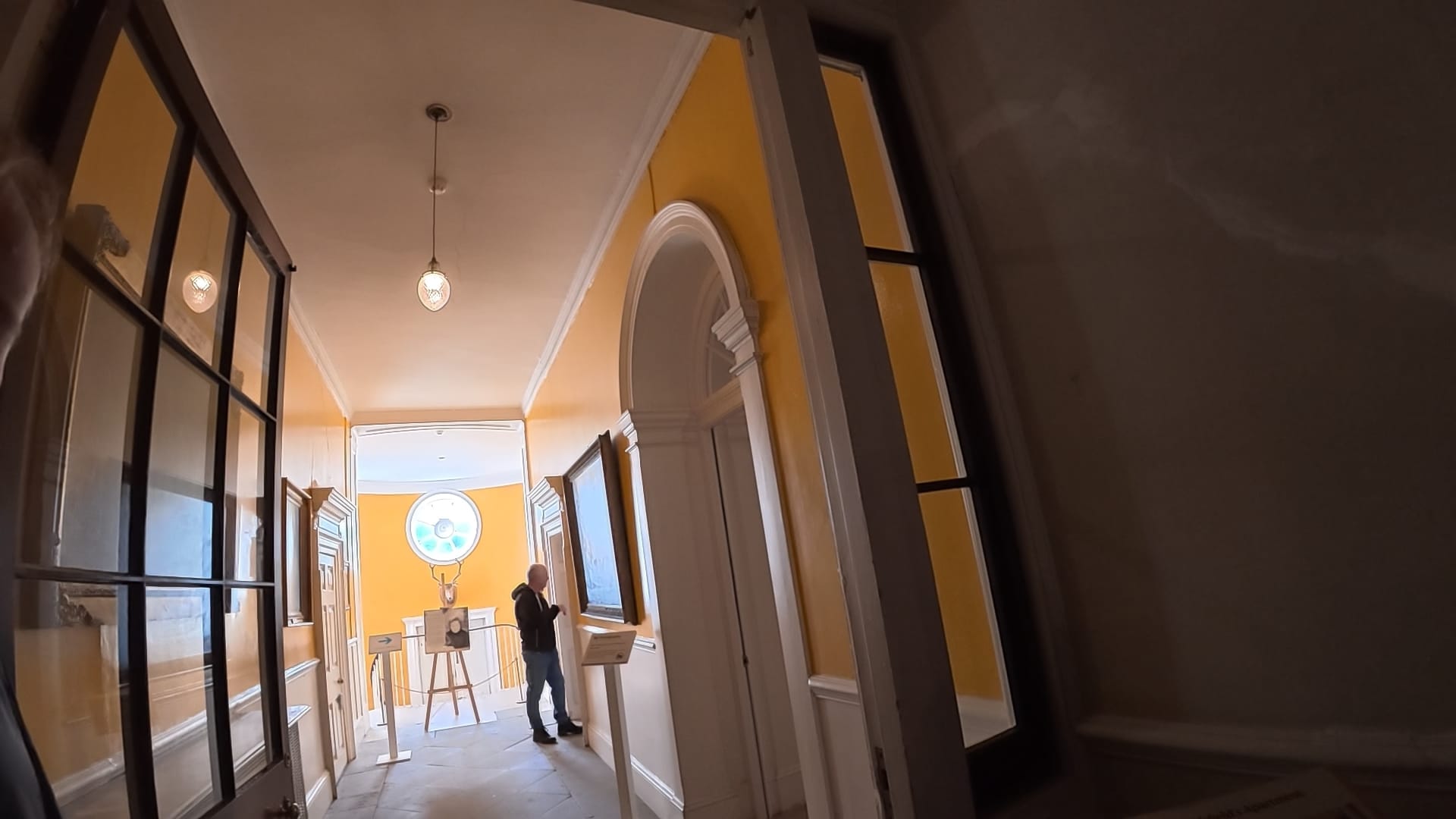 A door at the entrance to a hallway. There are indistinguishable pictures on the painted yellow walls. To the right, inside the hallway, is a doorway. No photography was allowed from this point.