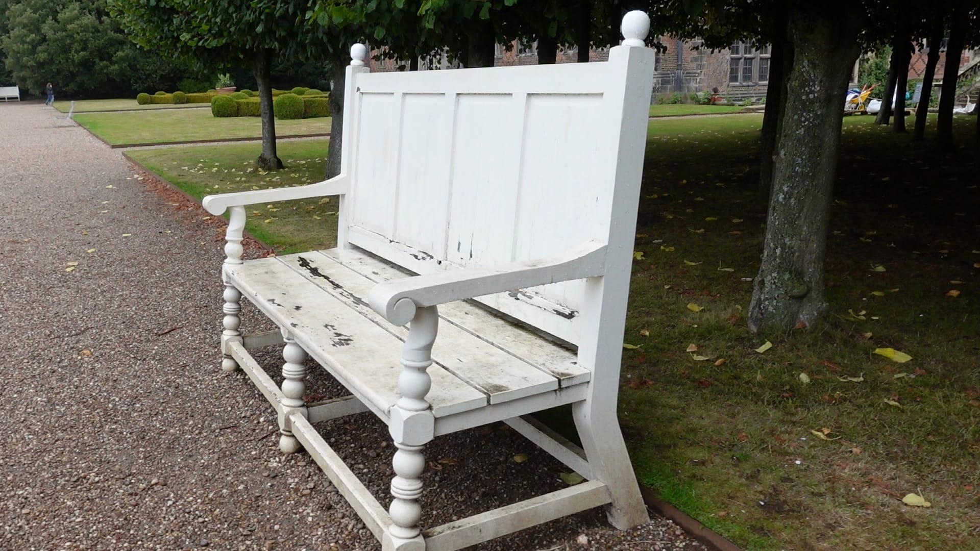 A large white bench is on the pathway. The seat of it is very clearly wet.