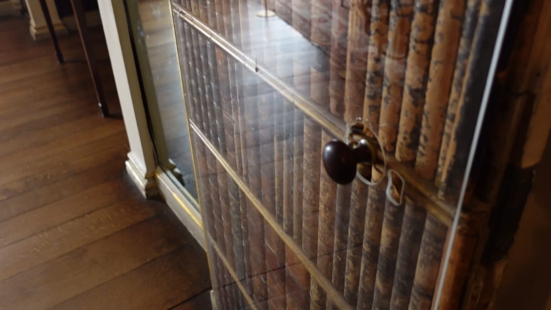 A door made of old book spines, covered by a clear plastic sheet for protection. A black door knob can be seen