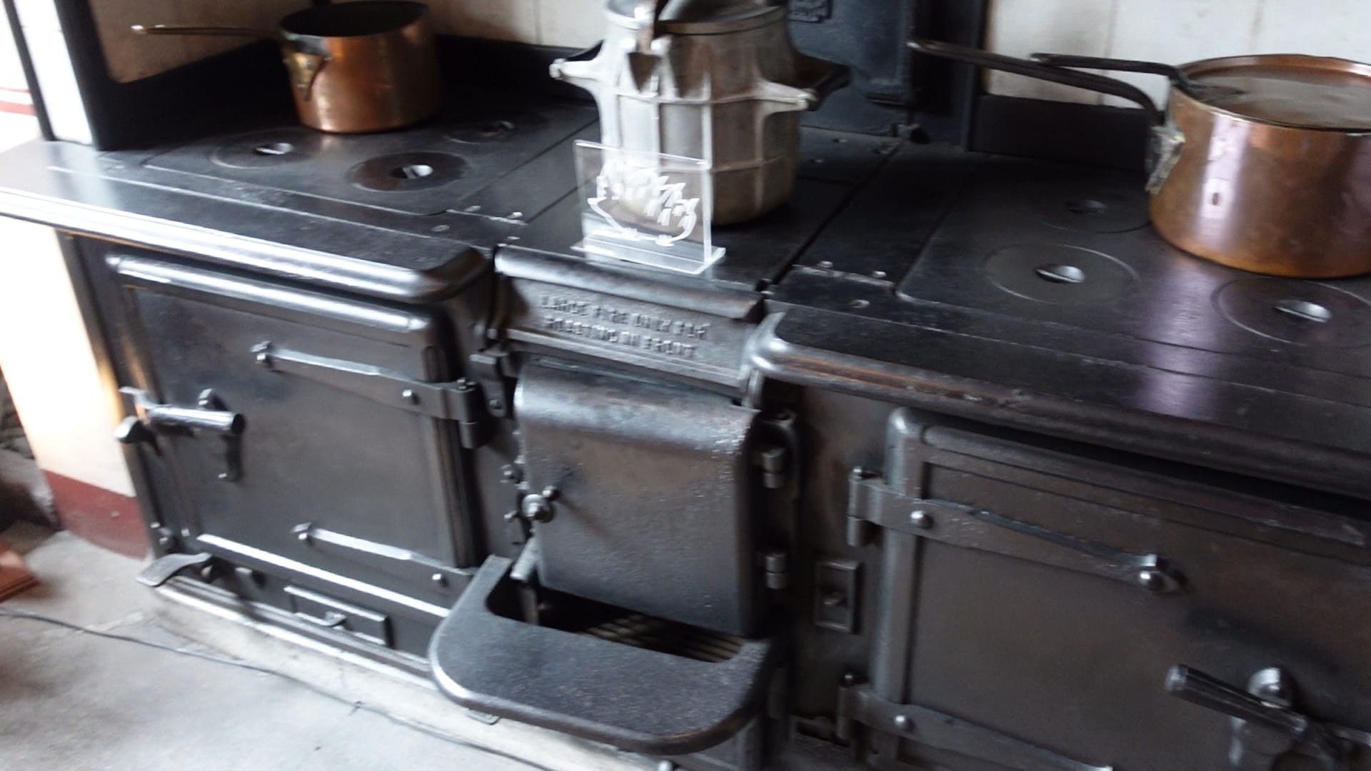 The bottom half of a large range cooker. There are two ovens and a place for the coal fire in the middle. Above each oven is a four ring hob. An old fashioned pressure cooker type pot is on the part of the oven above the coal fire.