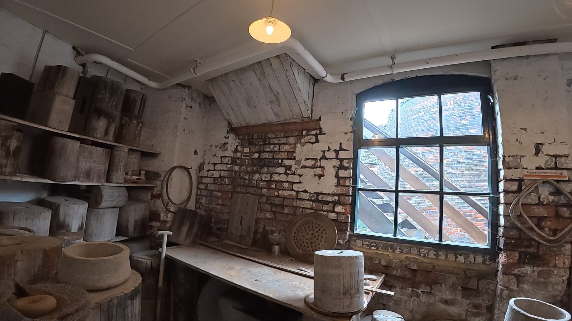 Old wooden workbench and shelves filled with saggars inside the Victorian pottery workshop.