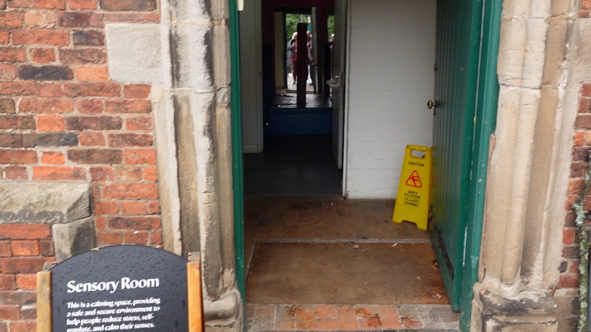 There is a black sign to the left that says "Sensory Room". The cameral is pointing inside and there is a soft play type area to be seen at the back, with some mirrors.