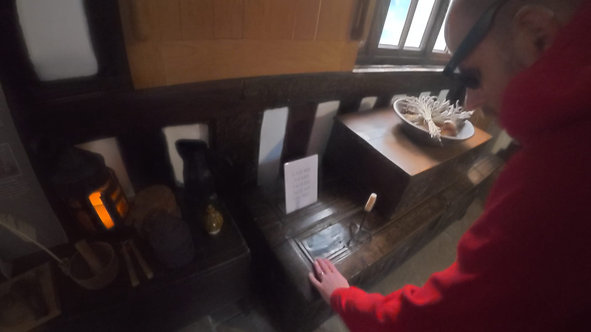 John is standing in front of the 600 year old chest, bending down to touch its lid. There is also a sign asking people not to sit on the chest
