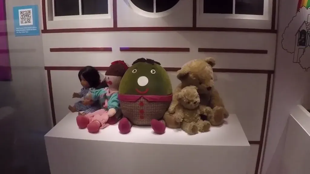 A display of vintage toys on a pedestal, including Hamble, Jemima, Humpty, and Big Ted and Little Ted, set against a playhouse backdrop. They were on the preschool TV programme Playschool.