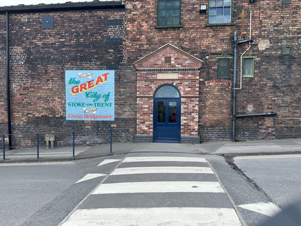 The entrance is a blue door with a painted sign next to it saying "the great city of Stoke-on-Trent with Emma Bridgewater"