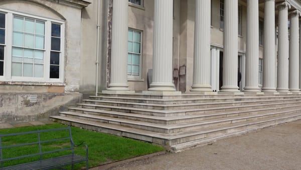Stairs leading up to ornate white columns at the entrance of the mansion